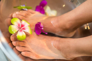 A person 's feet in the tub with flowers.